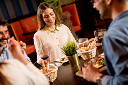 Group of young people having dinner in the restaurantの写真素材