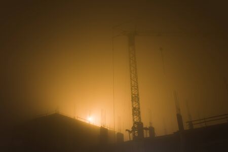 Tower crane at the construction site in the misty morning sunlightの写真素材