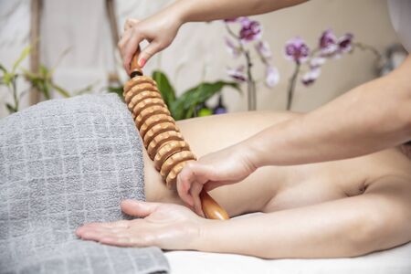 Closeup of the maderotherapy anti-cellulite massage with wooden roller massagerの写真素材