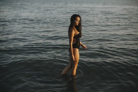 Pretty young woman walking in water at the beachの写真素材