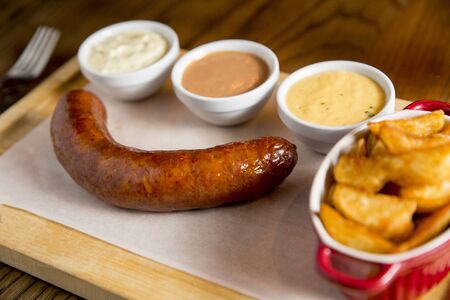 Sausage and potatoes with sauces on the wooden plateの写真素材