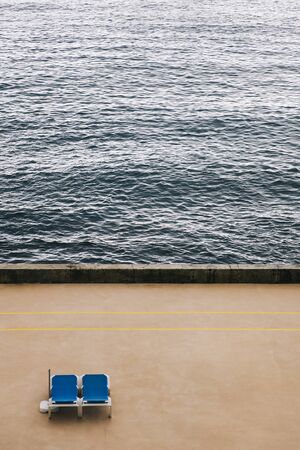Aerial view at two empty deckchairs on the ocean beach