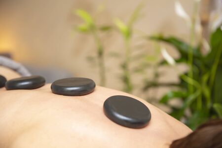 Young woman have a health spa relaxing stone therapy with hot volcanic stones on back