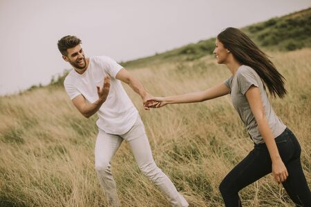 Happy young couple in love walking through grass fieldの写真素材