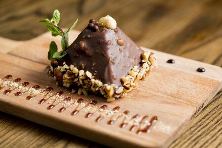 Chocolate pyramid shape cake with nuts on the wooden plateの写真素材