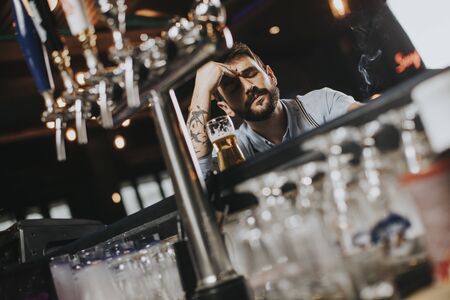 Young man drinking beer and smoking cigarette at pub in the night club