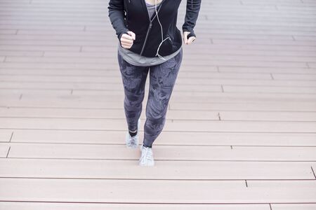 Young woman runing on the urban stairs and listening the musicの写真素材