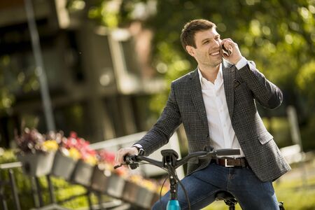 Handsome young businessman on the ebike using mobile phoneの写真素材