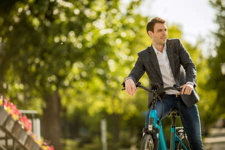 Handsome young businessman on the ebike using mobile phoneの写真素材