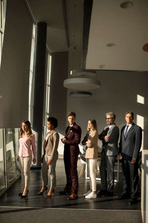Multiethnic corporate staff standing in row and looking in the camera at the modern officeの写真素材