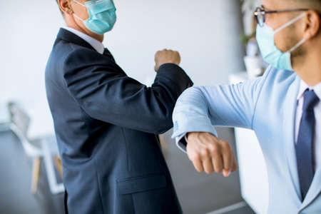 Two colleagues avoid a handshake when meeting in the office and greet with elbows bumping