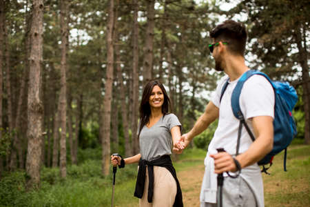 Smiling young couple walking with backpacks in the forest on a summer dayの写真素材