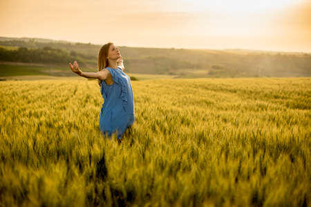 Young pregnant woman in blue dress in the summer field