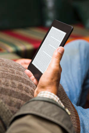 Senior man using an ebook reader in the sofaの写真素材