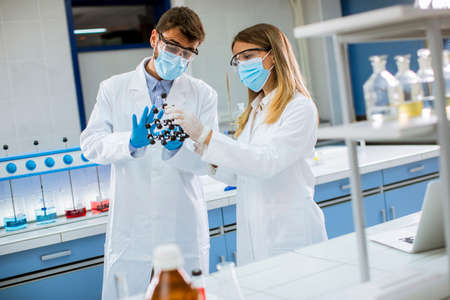 Young chemists with safety goggles holds molecular model in the lab