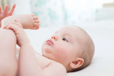 Cute baby girl lying and pulling her leg into her mouth