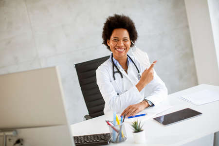 Female African American docor wear white uniform and taking off face mask in the hospital