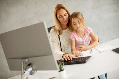 Working mother with her cute daughter in the officeの写真素材