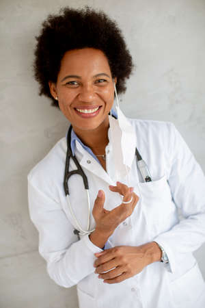 Female African American doctor wear white uniform and taking off face mask in the hospitalの写真素材