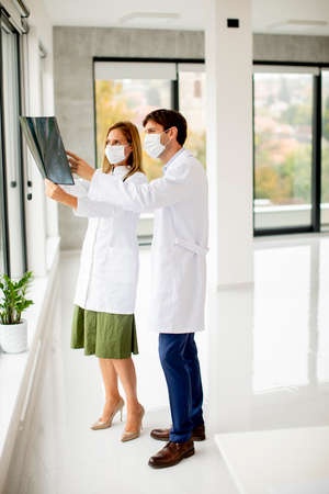 Team of doctors with protective facial masks examining xray in the officeの写真素材