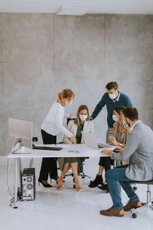 Team of business people working on project with facial masks as a virus protection in the officeの写真素材