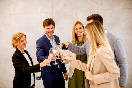 Group of excited business people celebrating and toasting with champagne in the office