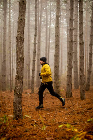 Handsome young man running in autumn forest and exercising for trail run marathon endurance raceの写真素材