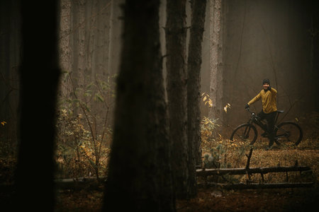 Handsome young man taking a brake during biking through autumn forest