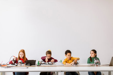 Group of happy kids programming electric toys and robots at robotics classroomの写真素材