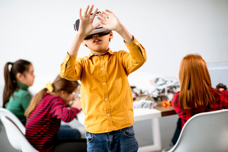 Cute little boy wearing VR virtual reality glasses in a robotics classroomの写真素材