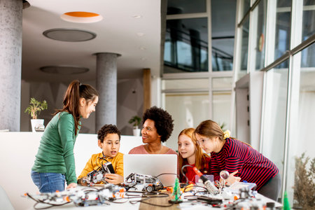 Group of happy kids with their African American female science teacher with laptop programming...