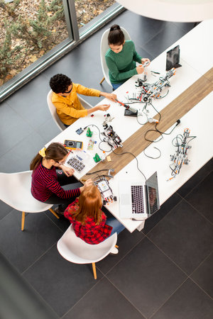 Group of happy kids programming electric toys and robots at robotics classroom