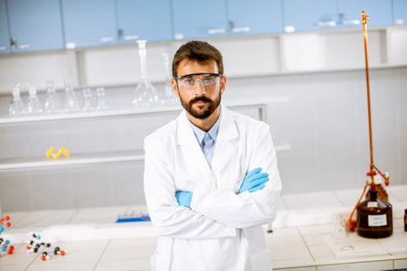 Handsome young scientist in white lab coat standing in the biomedical labの写真素材