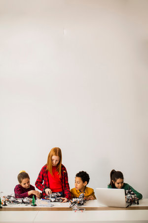 Group of happy kids programming electric toys and robots at robotics classroomの写真素材