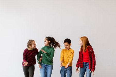 Portrait of cute little kids in jeans  talking and smiling, walking against the white wall
