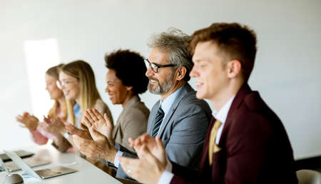 Multiethnic group of business people working together and applauding in after succesful meeting in the officeの写真素材