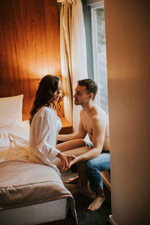 Loving and hugged couple on the bed in the room by the windowの写真素材