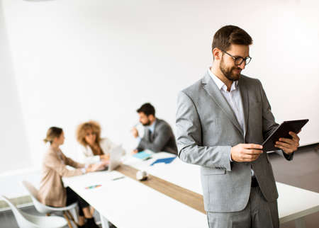 Handsome young modern businessman using digital tablet in the office