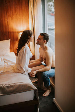 Loving and hugged couple on the bed in the room by the windowの写真素材