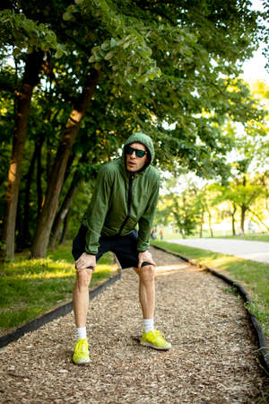 Handsome athletic young man having a break while doing workout in sunny green park