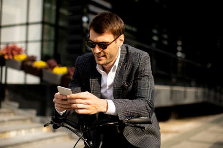Handsome young businessman on the ebike using mobile phoneの写真素材