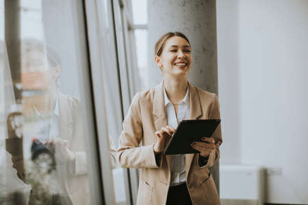 Pretty young woman holding digital tablet in modern officeの写真素材