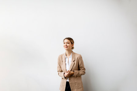 Pretty young woman standing by the white wall in modern officeの写真素材