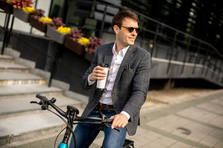 Handsome young businessman on the ebike with takeaway coffee cupの写真素材