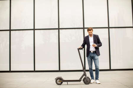 Handsome young businessman using mobile phone  on electric scooter