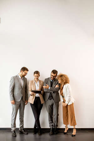 Multiethnic business people using digital tablet while standing by the wall in the modern officeの写真素材