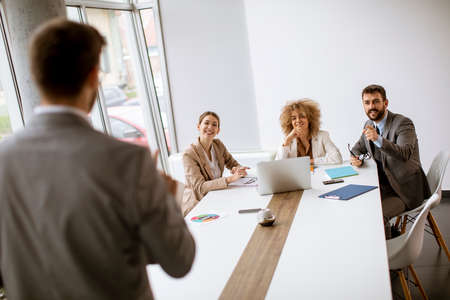 Young business people sitting at meeting table in conference room discussing work and planning...
