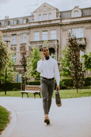 Handsome young African American businessman using a mobile phone on a street