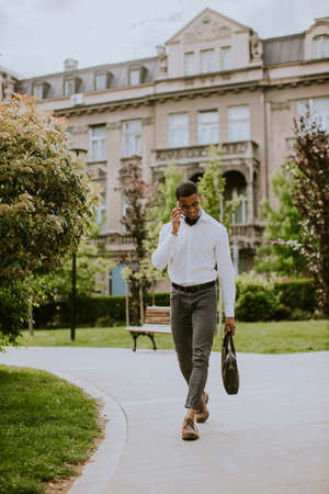 Handsome young African American businessman using a mobile phone on a streetの写真素材