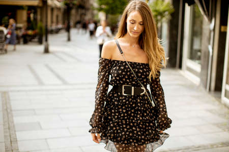 Pretty young long hair brunette woman walking on the city streetの写真素材